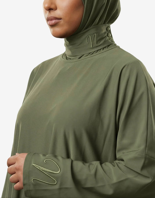 Femme portant un burkini 3 pièces vert avec cagoule intégrée - coupe ample et confortable - zoom sur les détails de la cagoule et du tissu ainsi que le logo